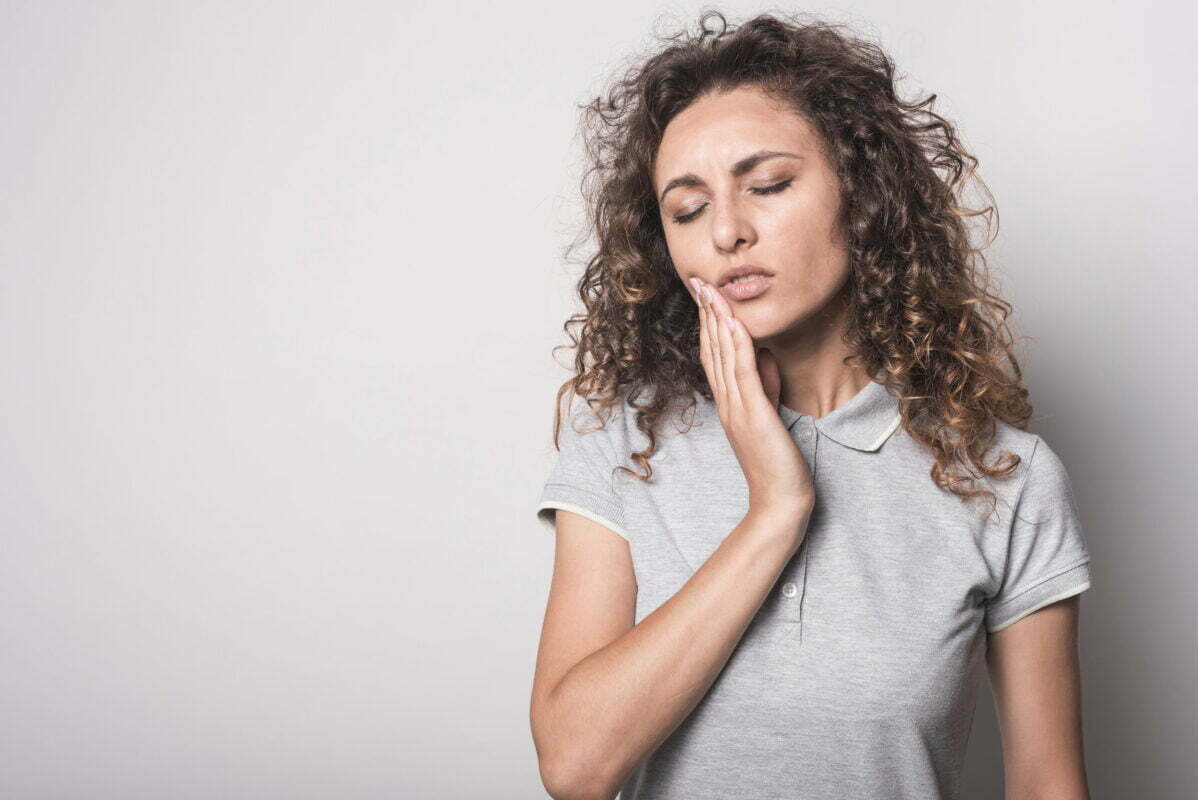 close-up-woman-with-curly-hair-suffering-from-toothache-gray-background.jpg