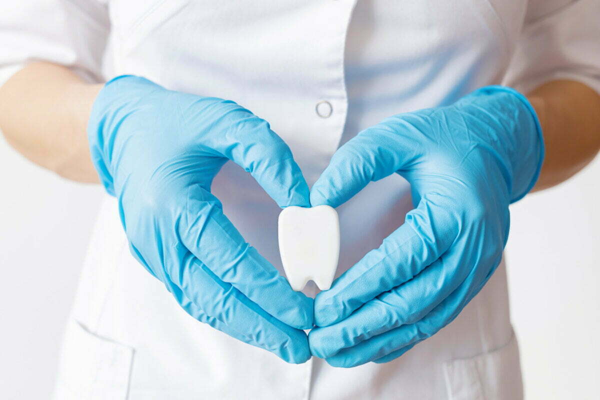 hands-dentist-doctor-blue-gloves-are-holding-tooth-model-form-heart.jpg