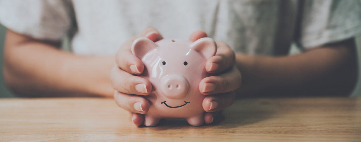 man-hand-holding-piggy-bank-wood-table.jpg